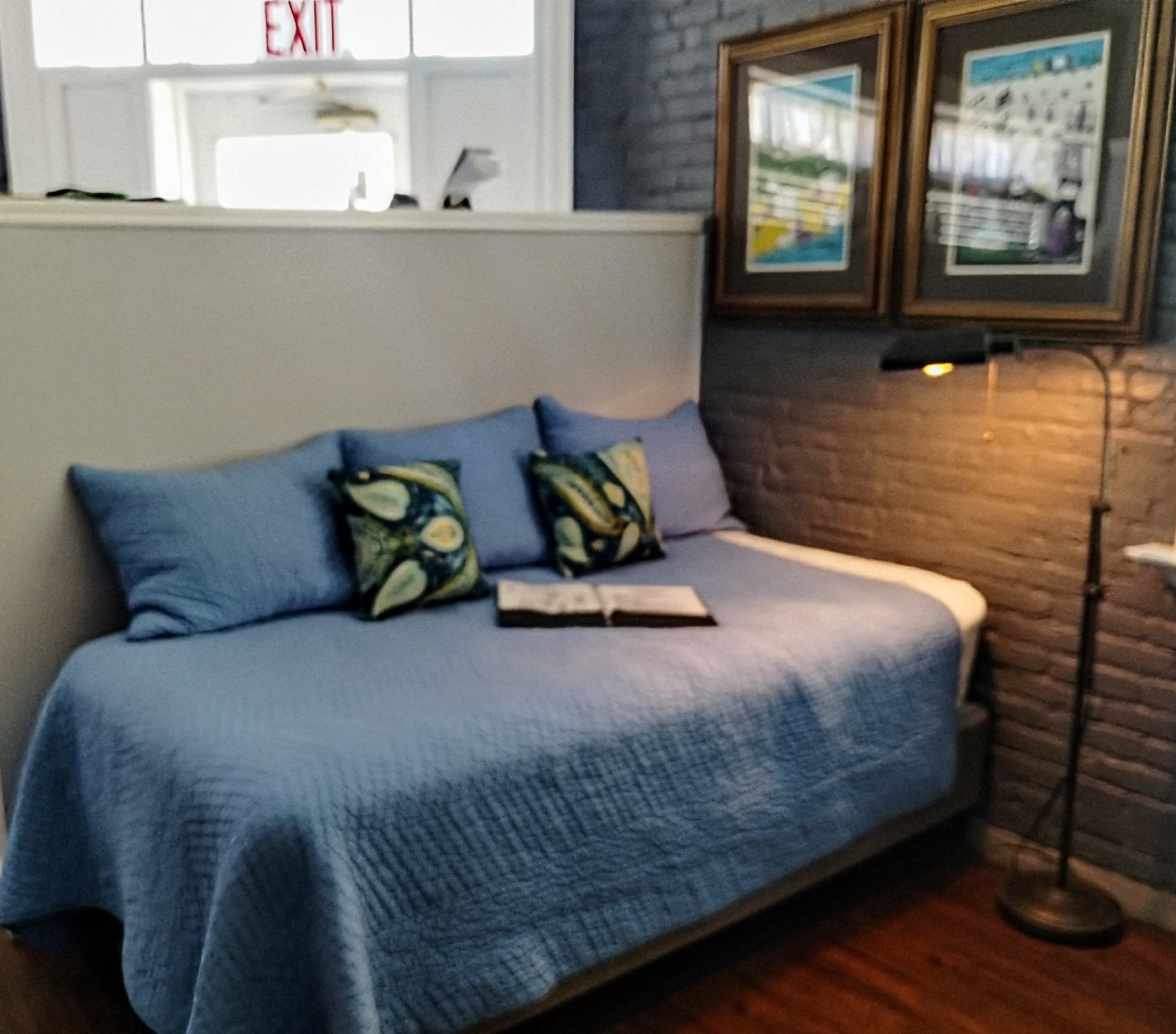 A daybed with blue bedding and decorative pillows in a sunny room.