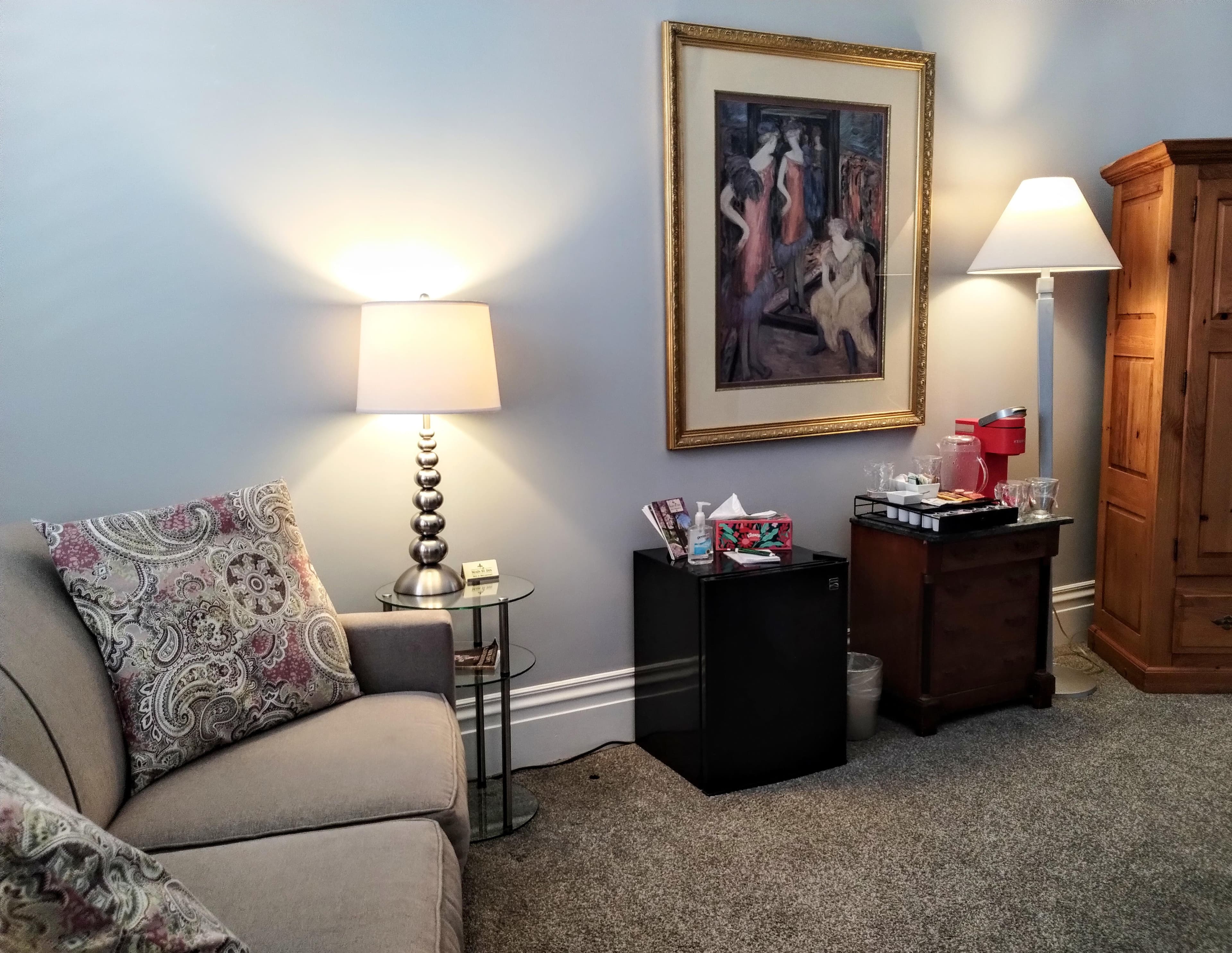 An inviting room with a beige couch, two lamps, a framed painting, and two side tables.