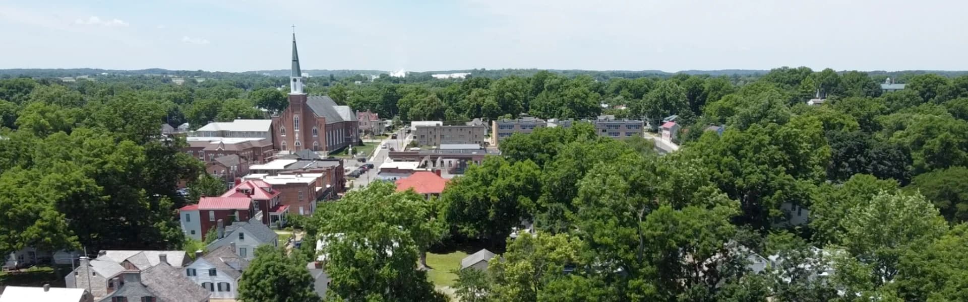 Aerial view of a small town featuring a church and surrounding greenery.