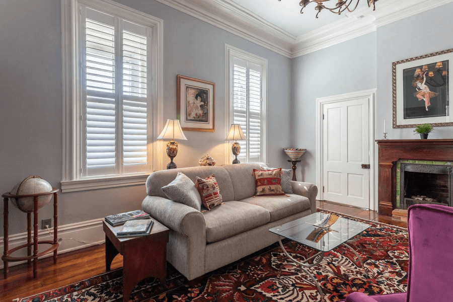 A cozy living room featuring a light gray sofa, decorative pillows, a glass coffee table, and warm lighting from table lamps.