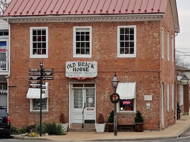 Historic Old Brick House with a red tin roof and open sign.