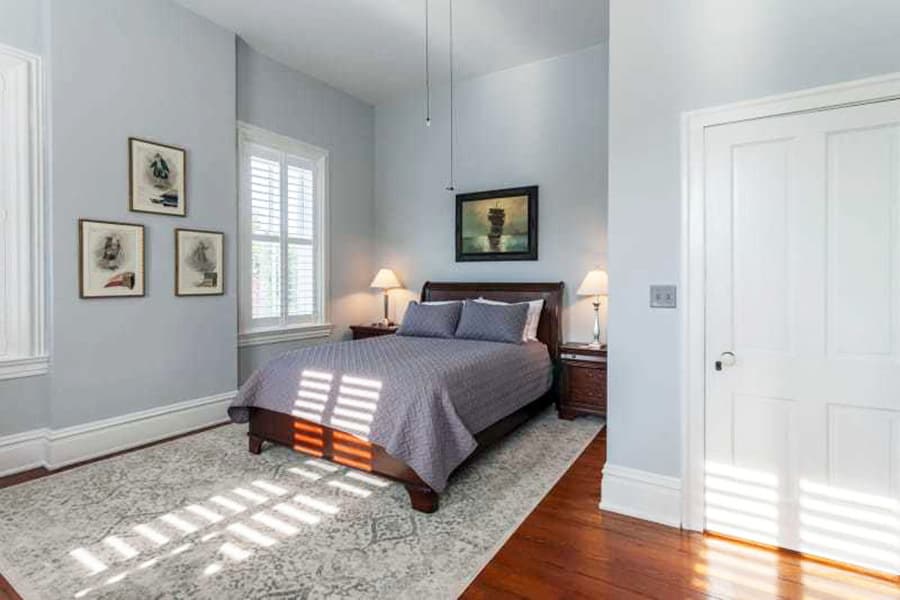 Cozy bedroom with a bed, two lamps, artwork on the walls, and a decorative rug.
