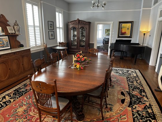 Large oval wooden dining room table on top of rug that is on the hardwood floor.