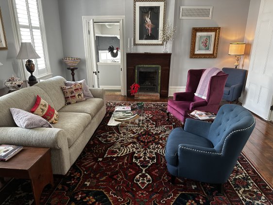 White couch on left with blue and purple chairs on right with the fireplace in the background.